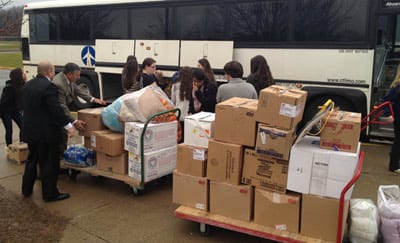 State Senator Len Fasano (left, leaning) helps East Haven High School students load a bus full of provisions bound for victims of Super Storm Sandy in Staten Island, NY. East Haven students and their U.S. History teacher, Tony Vaspasiano collected clothes, school supplies, toys and other goods during a donation drive. Andy Anastasio of Connecticut Limousine provided the bus and transportation free of charge.